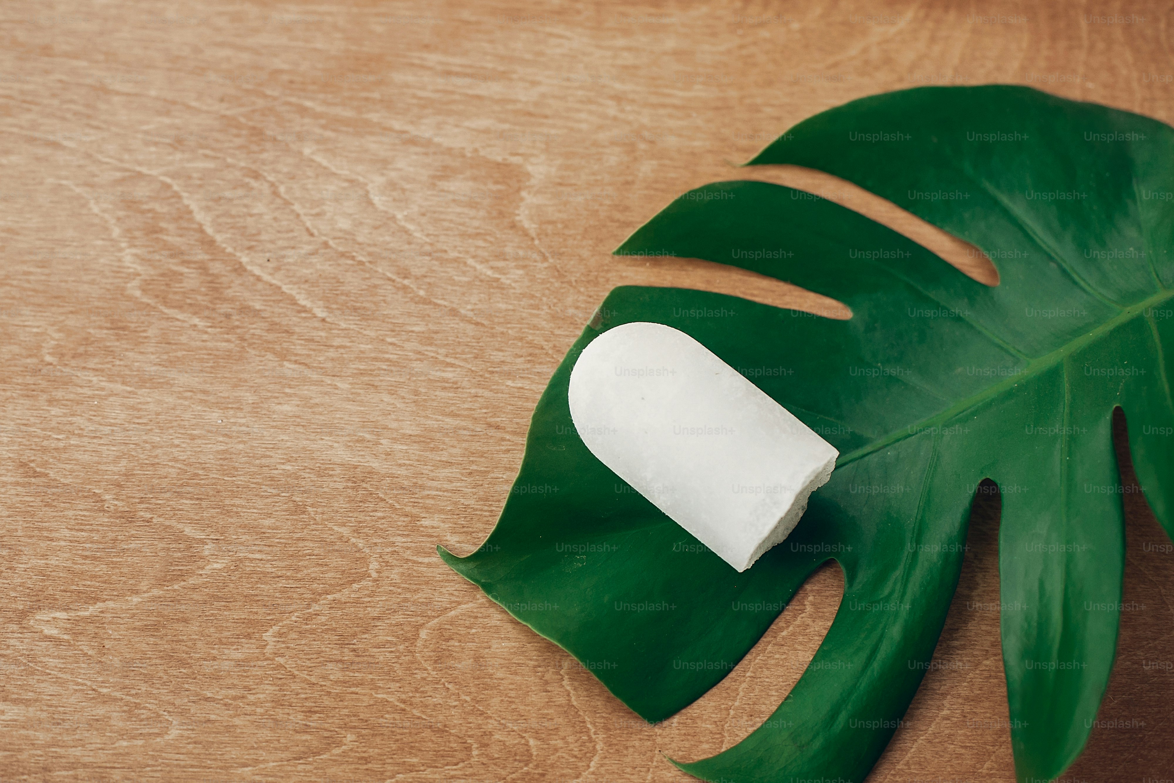 Natural eco crystal deodorant anulit on wooden background with green monstera leaf. Plastic free beauty essentials. Zero waste concept, copy space. Sustainable lifestyle