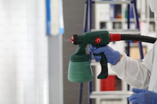 Man stands next to stepladder and holds spray gun in his hands. Wall painting concept