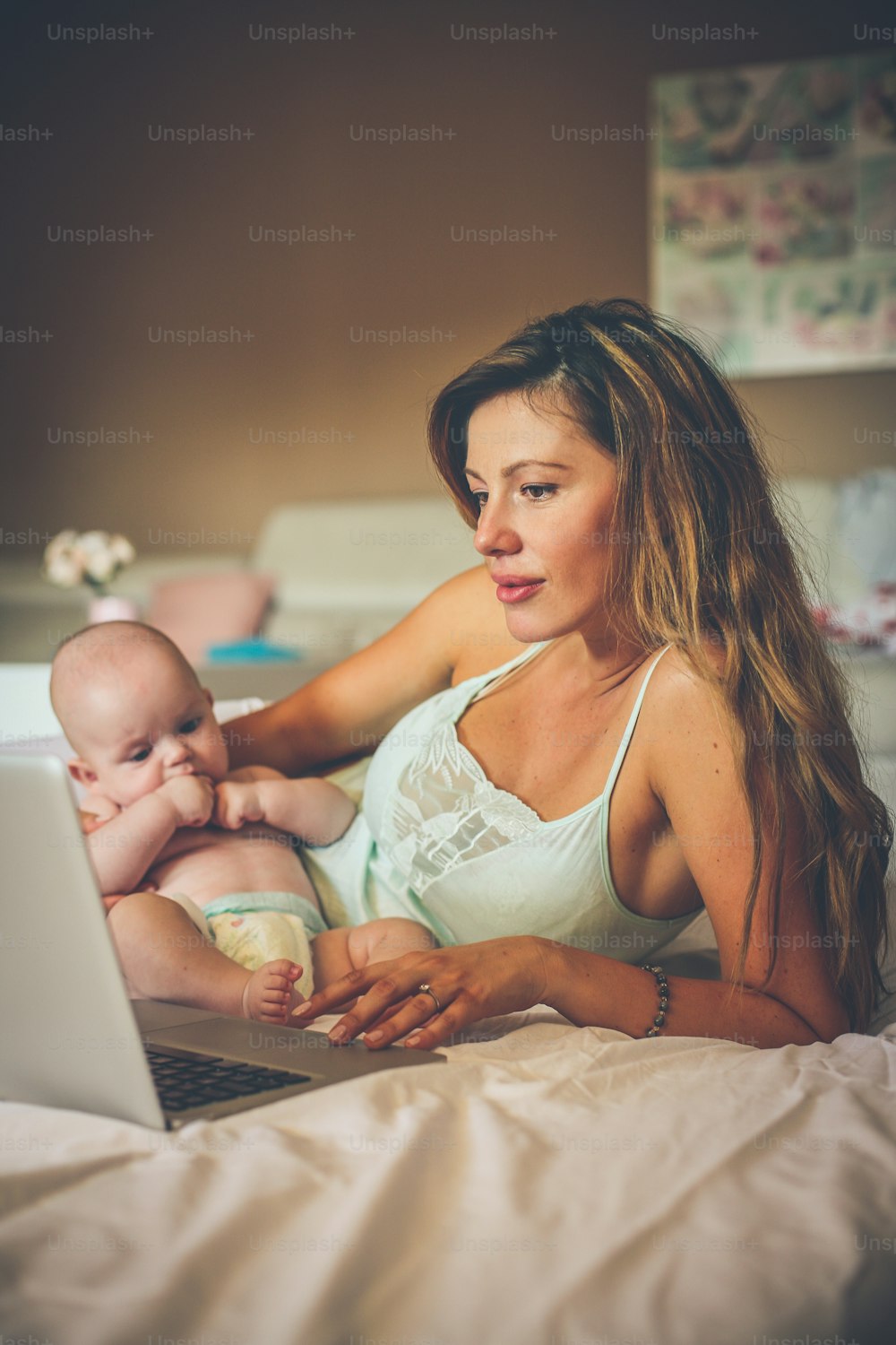 Mother working on laptop with her baby in arms.  Business women.