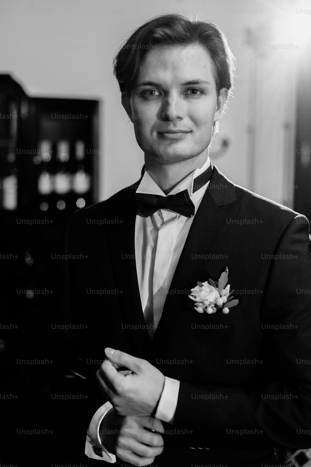 Novio guapo esperando a la novia en la habitación del hotel de lujo, mañana antes de la ceremonia de la boda, novio romántico en traje elegante posando en el interior