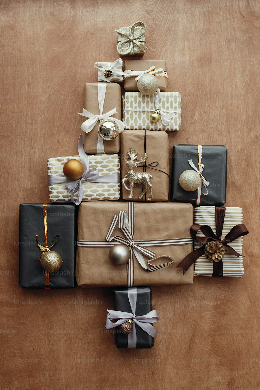 Eleganti scatole regalo natalizie con ornamenti a forma di albero su sfondo rustico in legno. Il nero moderno e l'oro presentano una posa piatta. Auguri di buone feste, foto creativa festosa. Buon Natale