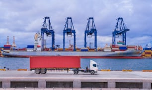 Cargo ship and truck at seaport waiting for container dock crane  shipment harbour loading container boxes import and export commercial trade business logistic and transportation of international.