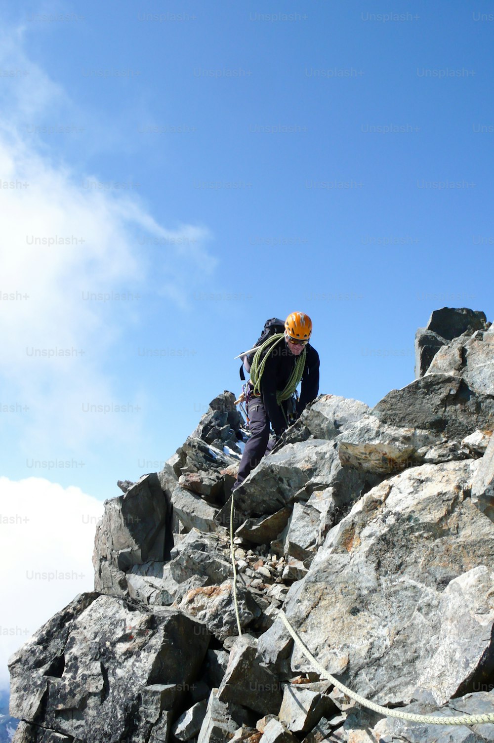 mountain guide on a steep and exposed rocky ridge on his way to a high alpine summit with a client on a beautiful day in the Swiss Alps