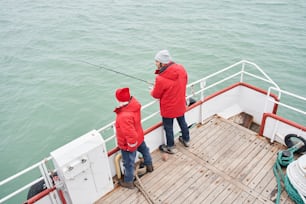 Vista ad angolo alto dei due pescatori che tengono la canna da pesca per combattere i pesci nell'oceano o in mare. Attività sportive o concetto di pesca e acquacoltura. Immagine