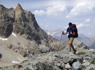 Männlicher Bergsteiger wandert auf einem Wanderweg auf einer trockenen und staubigen Gletschermoräne in den französischen Alpen