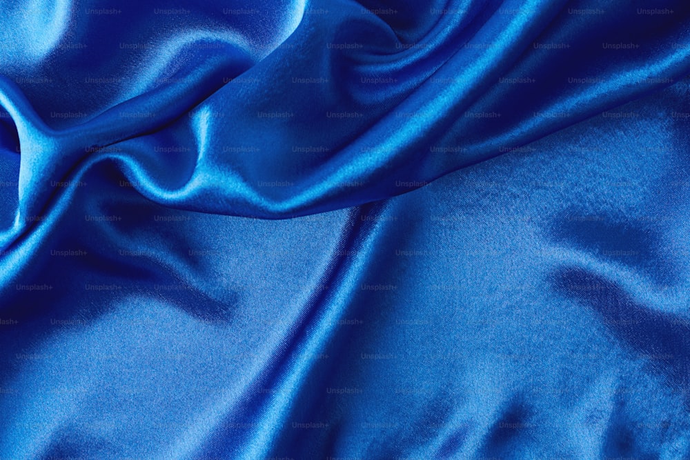Fond de soie bleue avec des plis.  Texture abstraite de la surface satinée ondulée