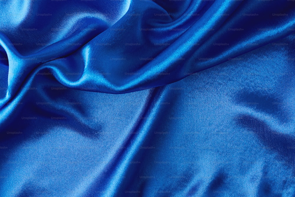 Blue silk background with folds.  Abstract texture of rippled satin surface
