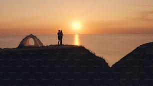 The man and woman standing near the campsite tent on the sea shore