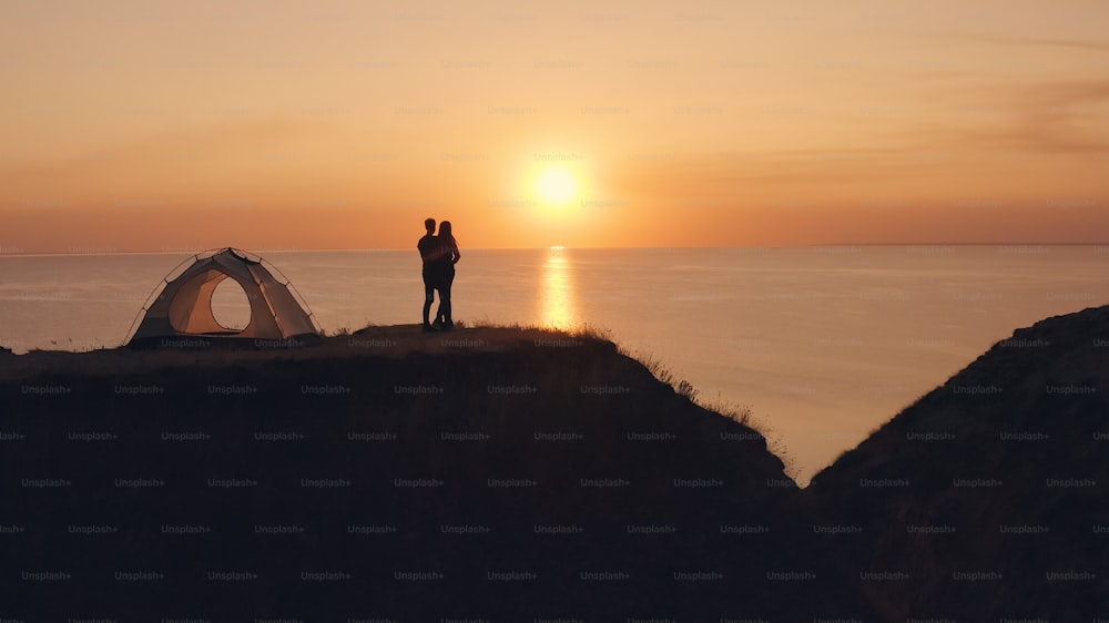 L’homme et la femme debout près de la tente de camping au bord de la mer
