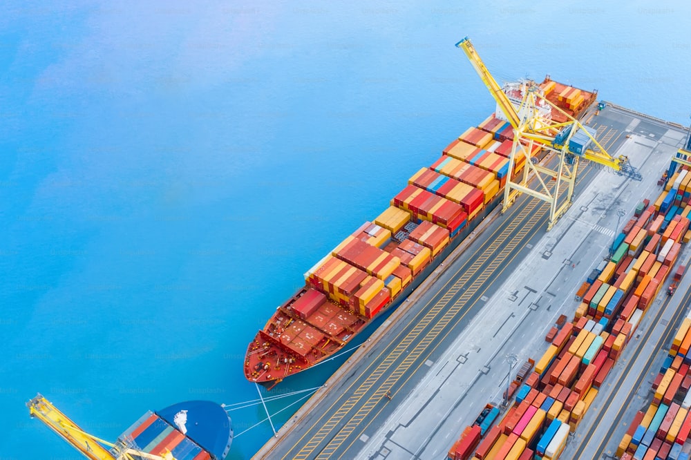 Ship with cargo containers at the marina of an industrial port, aerial view