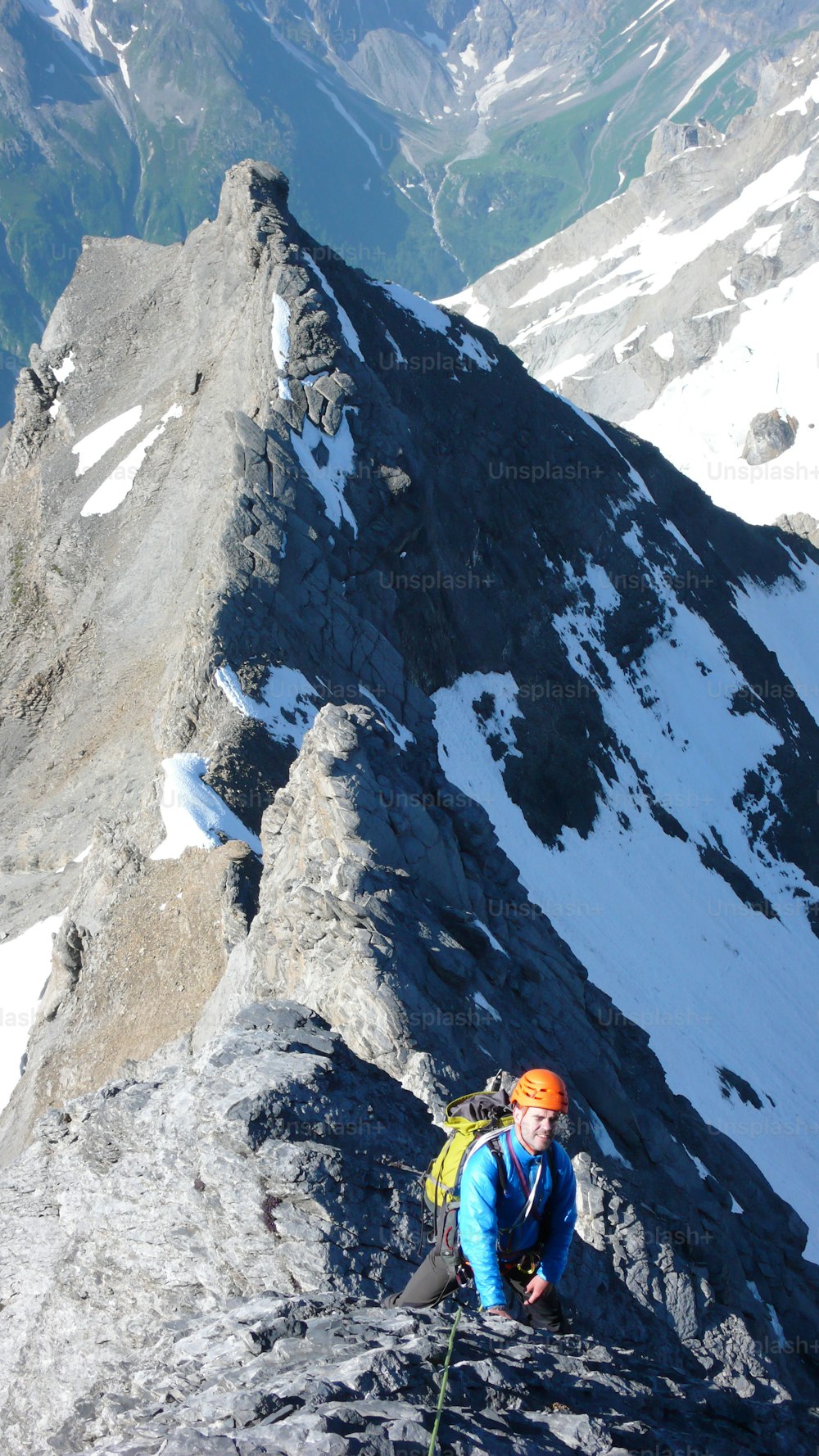 스위스 알프스의 아름다운 여름날 가파르고 노출된 바위 능선의 높은 고산 정상으로 가는 남성 산악인