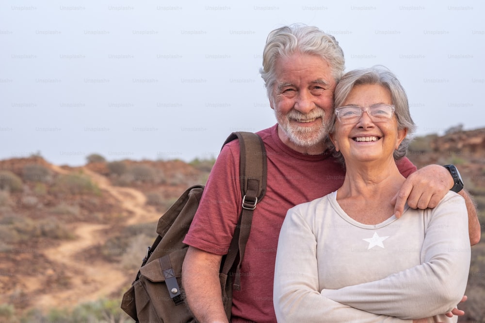 Portrait of beautiful senior couple gray-haired hugging in outdoors excursion, active and healthy lifestyle