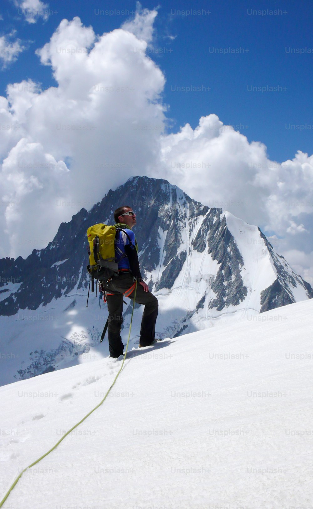 Männlicher Bergsteiger blickt auf den Gipfel und sein Ziel, während er auf einem hochalpinen Gletscher in den Schweizer Alpen unterhalb des Loetschentaler Breithorns steht