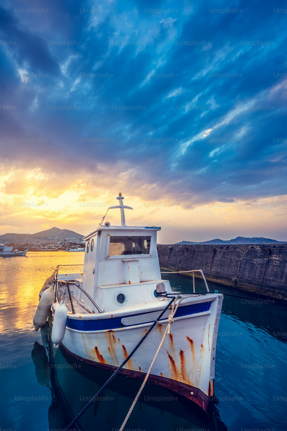 극적인 하늘과 함께 일몰에 나오우사 항구에 있는 오래된 어선. 파로스 엘슬란, 그리스