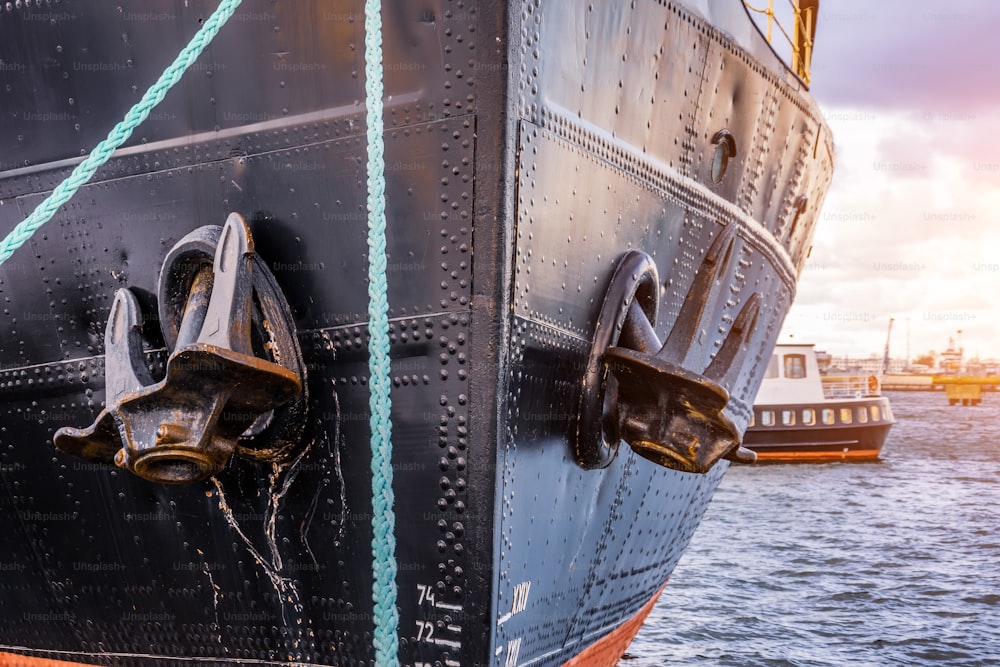 The nose and anchors of a black icebreaker moored in the port