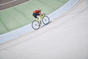 Top view of man in sports clothing cycling on track outdoors