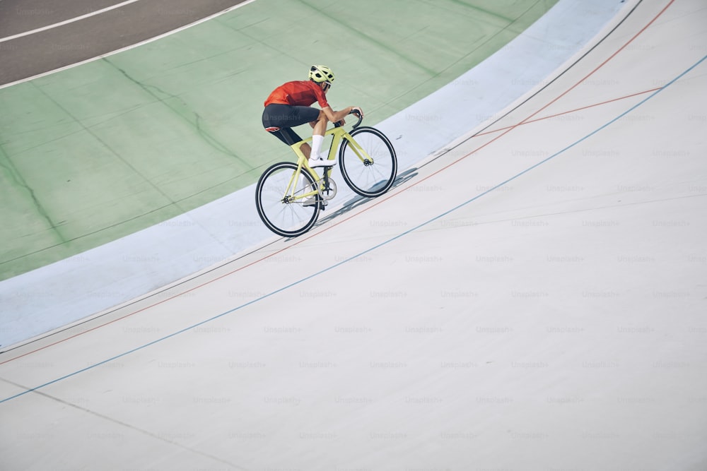 Top view of man in sports clothing cycling on track outdoors