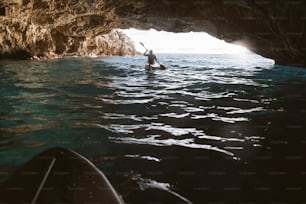 Homme pagayant en kayak dans une grotte, faisant du kayak et de la spéléologie en même temps.