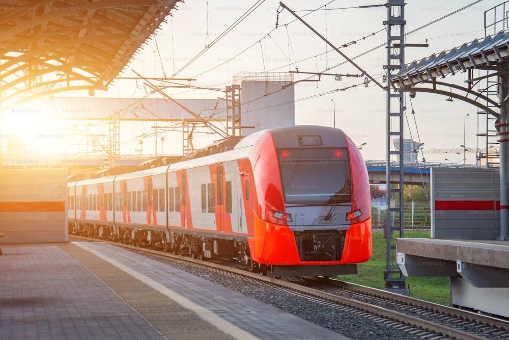 Passenger electric train departs from the station platform and rides on the turn of the railway line