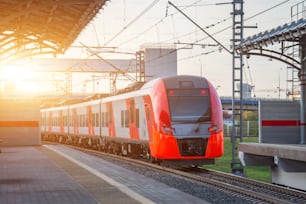 Passenger electric train departs from the station platform and rides on the turn of the railway line