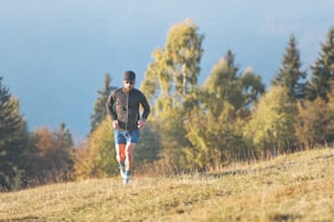 Un hombre corre a través de un prado montañoso. En otoño