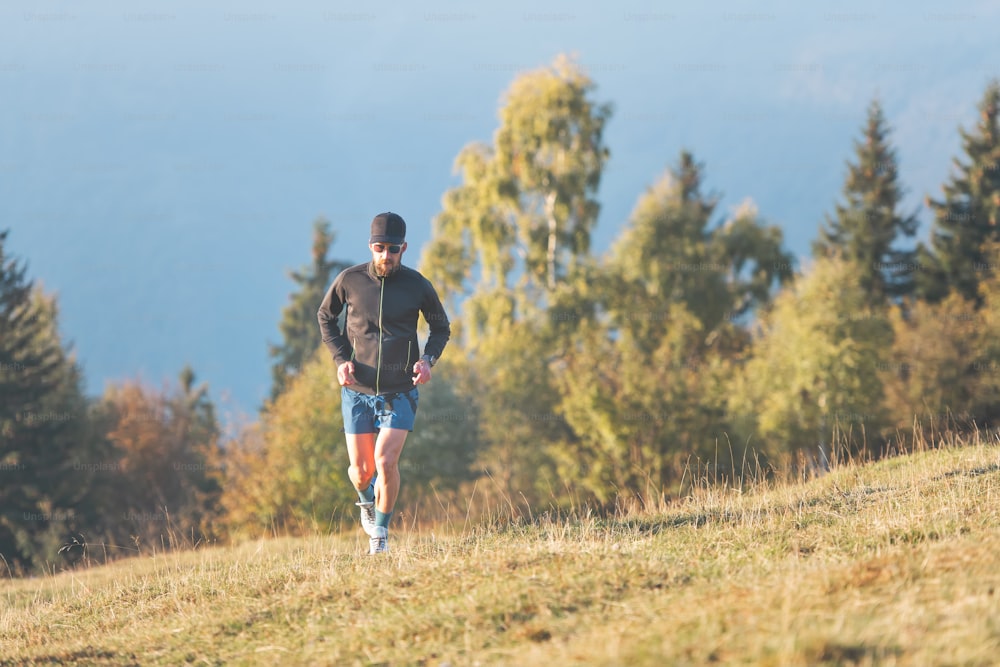 A man runs across a hilly meadow. In autumn