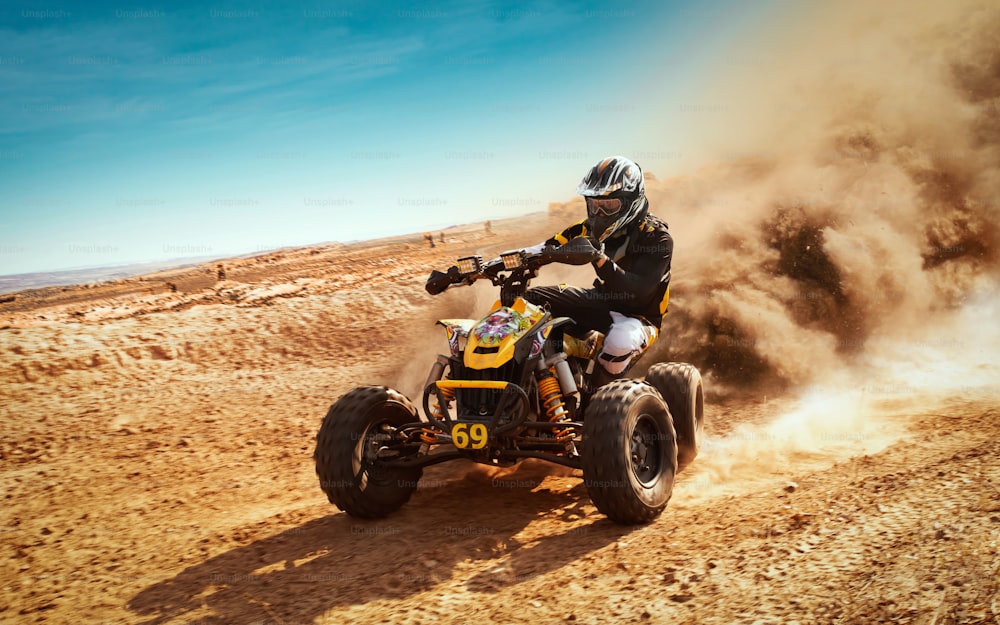 Quad in nuvola di polvere, cava di sabbia sullo sfondo. ATV Rider in azione.