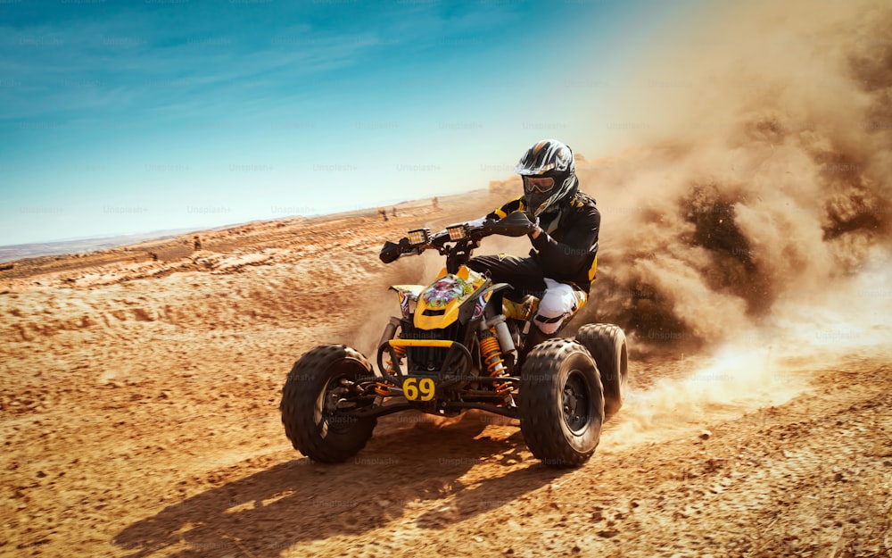 砂埃の雲、砂の採石場を背景にしたクワッドバイク。アクションのATVライダー。