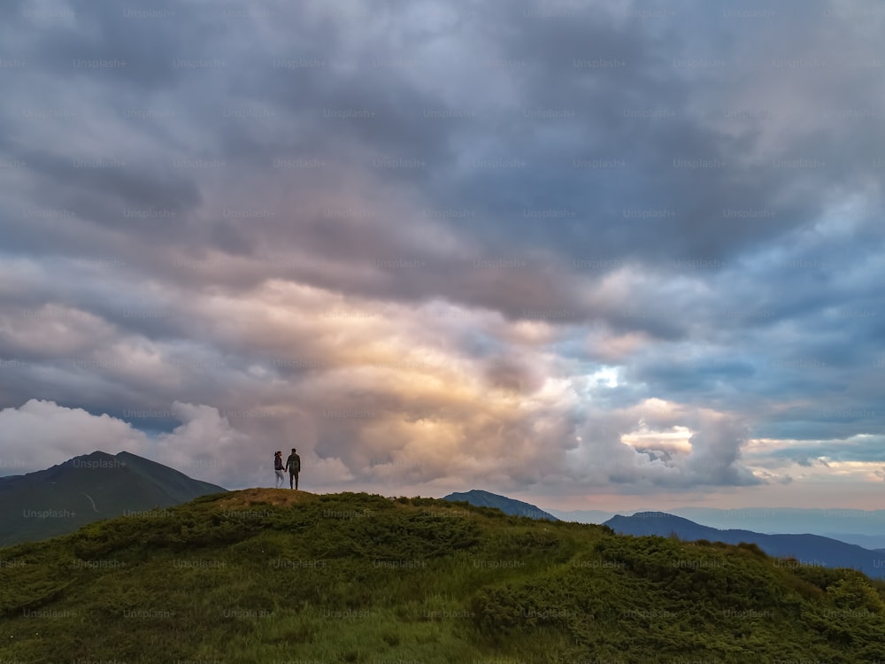 A mulher e o homem de pé na montanha com uma vista pitoresca