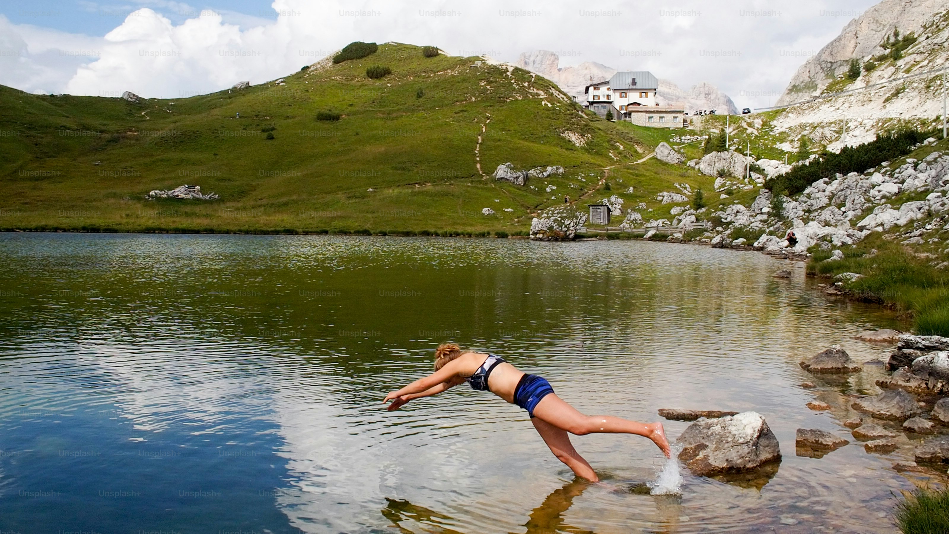 Uma loira atraente em seus vinte anos mergulhando em um lago de montanha