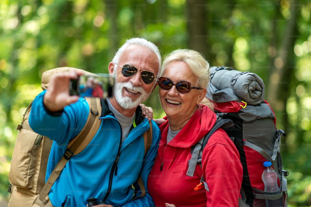 Active senior couple hiking in forest with backpacks, enjoying their adventure.