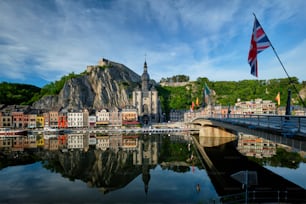 Malerische Stadt Dinant, Zitadelle von Dinant und Stiftskirche Notre Dame de Dinant und Pont Charles de Gaulle Brücke über die Maas mit Flagge. Belgische Provinz Namur, Blegium