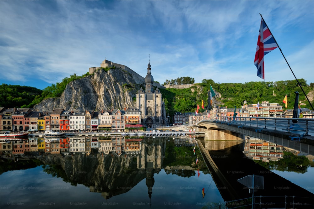 Picturesque Dinant town, Dinant Citadel and Collegiate Church of Notre Dame de Dinant and Pont Charles de Gaulle bridge over Meuse river with flag. Belgian province of Namur, Blegium