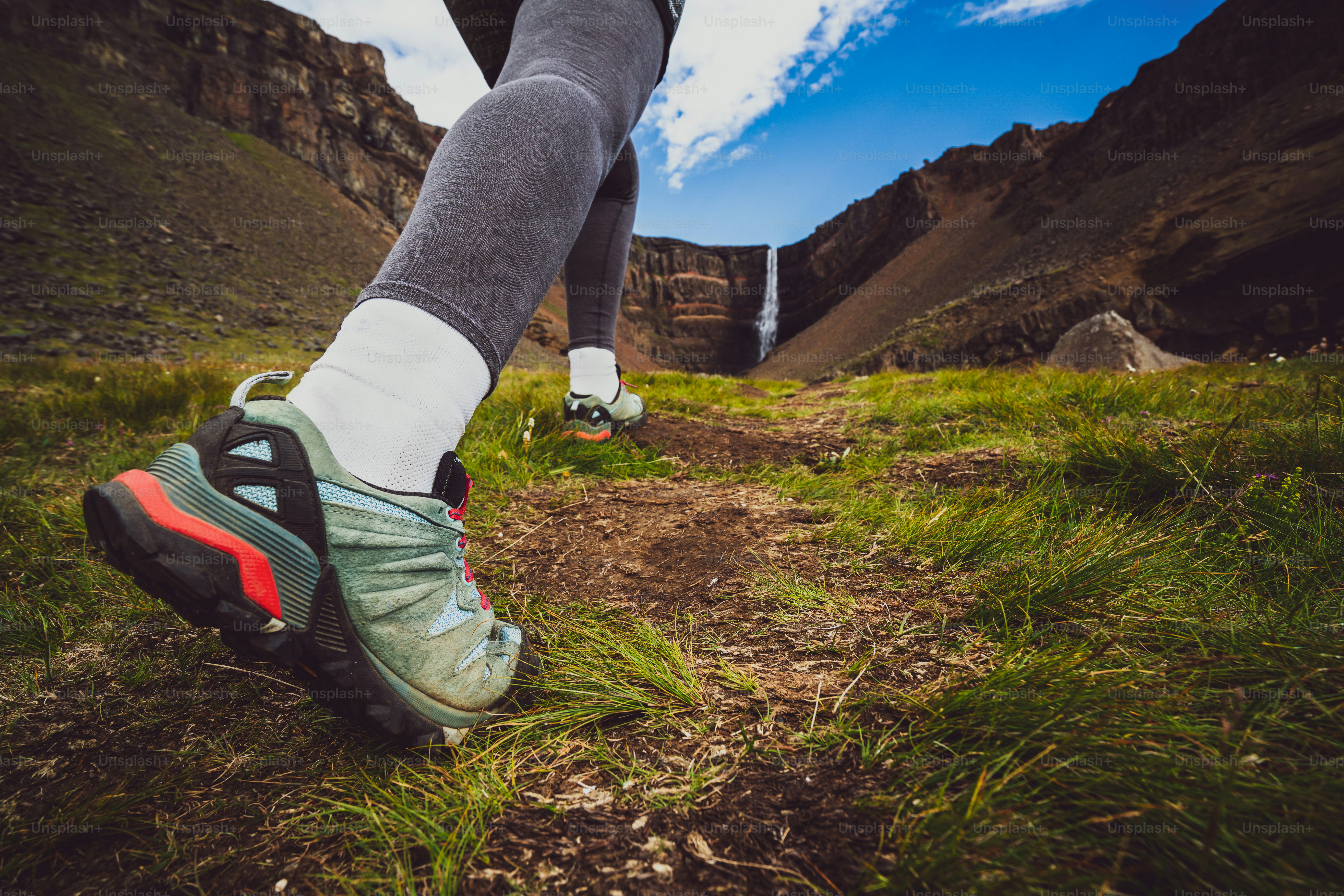 Woman traveler trekking in Icelandic summer landscape at the Hengifoss waterfall in Iceland. The waterfall is situated in the eastern part of Iceland.