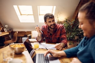 Happy college roommates communicating while learning together at home. Focus is on man.