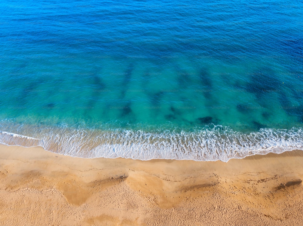 Aerial view of an idyllic sea sandy beach with an incoming azure wave. The concept of holidays in tropical countries and relaxation. Background for travel and vacation