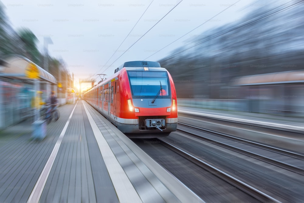 Tren rojo de alta velocidad de pasajeros con desenfoque de movimiento en la estación