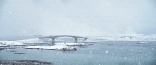 Fredvang bridges in heavy snowfall in winter with fishing ship. Lofoten islands, Norway