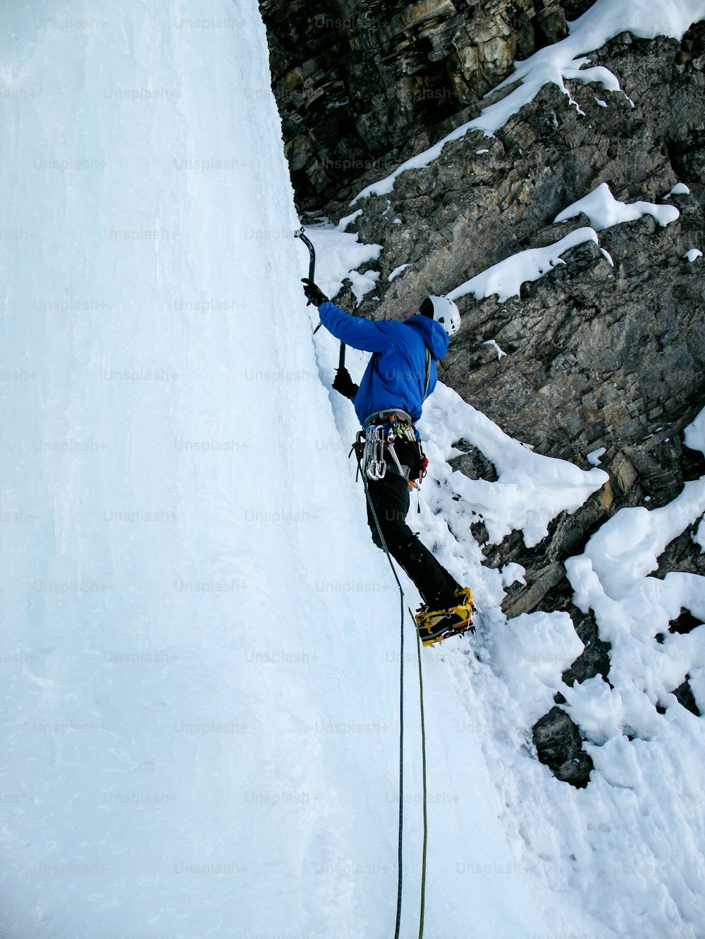 Escalador de hielo masculino en una empinada cascada de hielo en Suiza, cerca de Davos