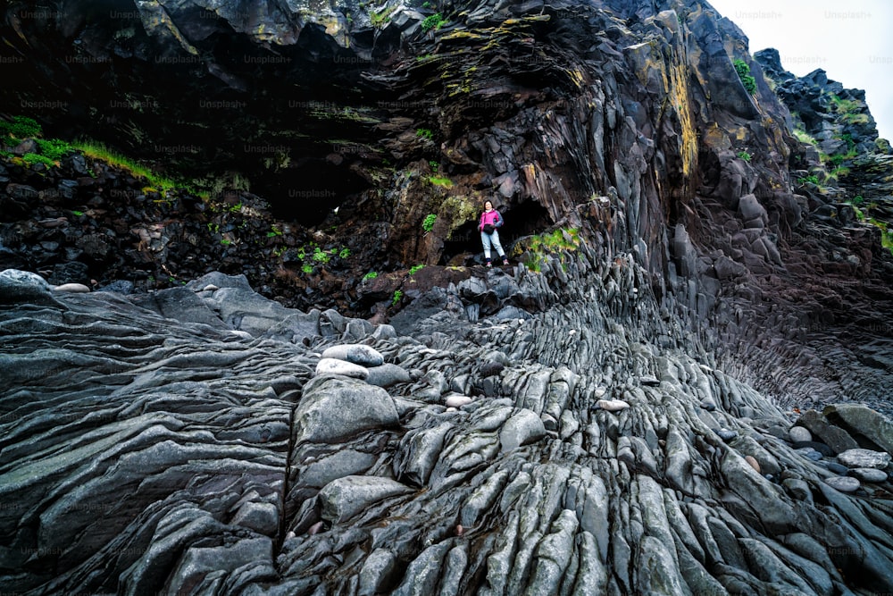 Escursionista viaggiatore nel paesaggio costiero roccioso a Hellnar, Islanda. Hellnar era tra i più grandi villaggi di pescatori sotto la calotta glaciale di Snaefellsjokull nell'Islanda occidentale.