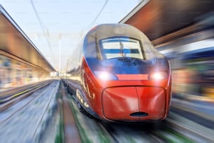 Treno passeggeri Intercity con effetto motion blur sulla piattaforma ferroviaria