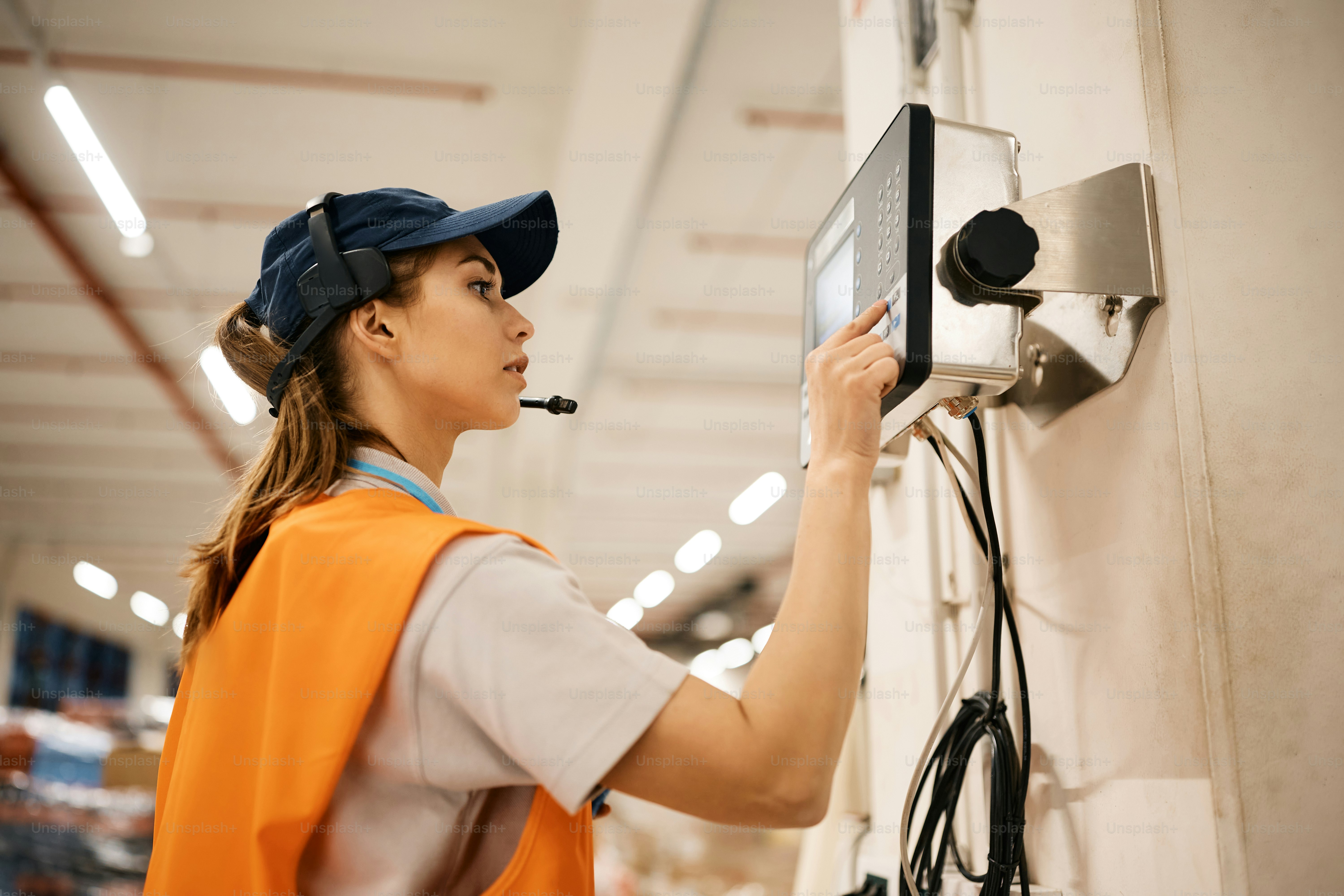 Lavoratrice che inserisce il codice sulla macchina industriale mentre lavora al magazzino di distribuzione.