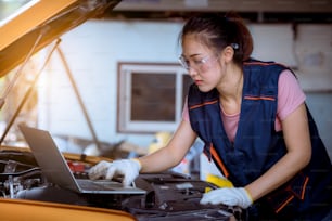 A woman car mechanic repairing car with open hood view and checking level motor oil for refill or clean in car garage service
