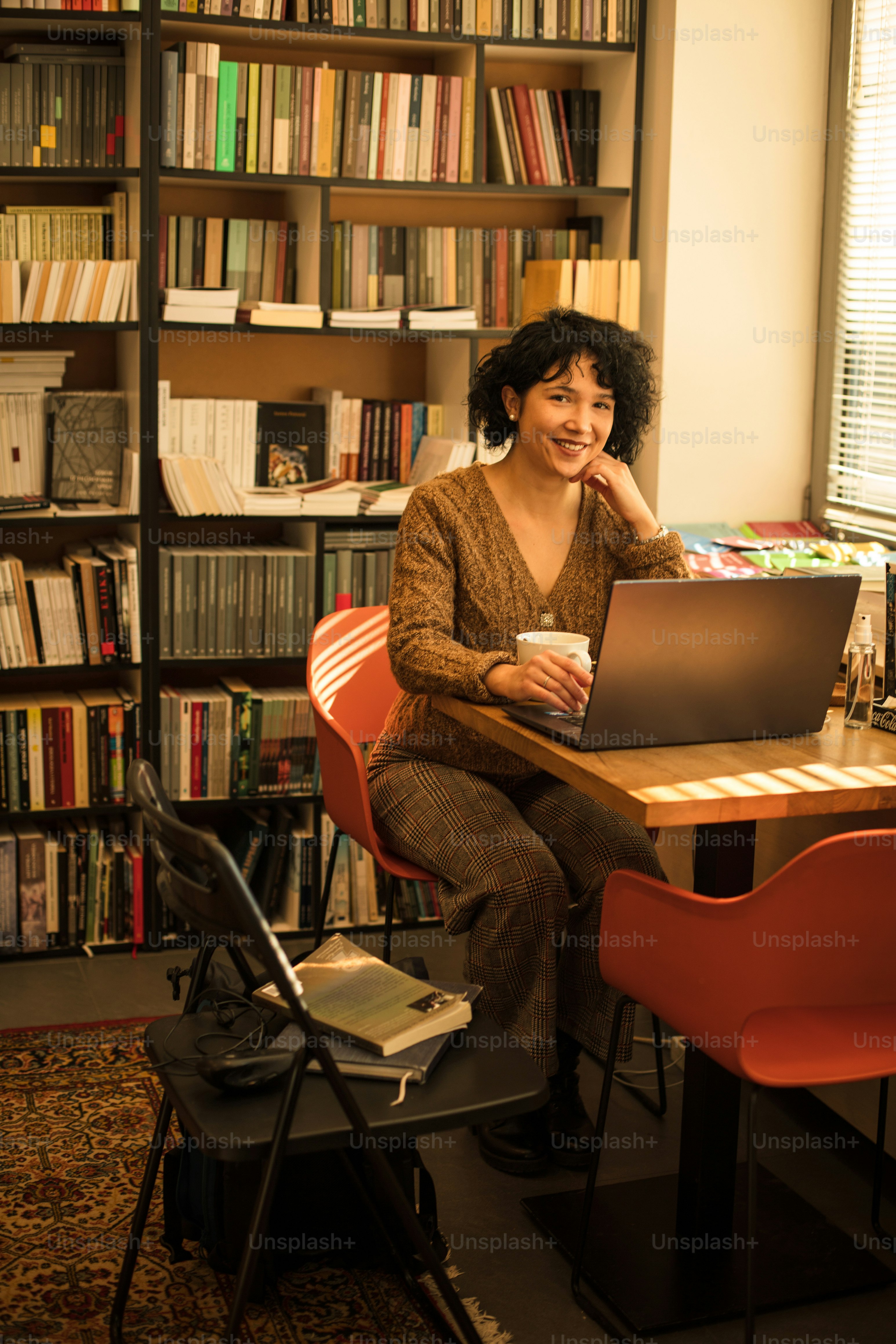 Woman in library using laptop. Looking at camera.