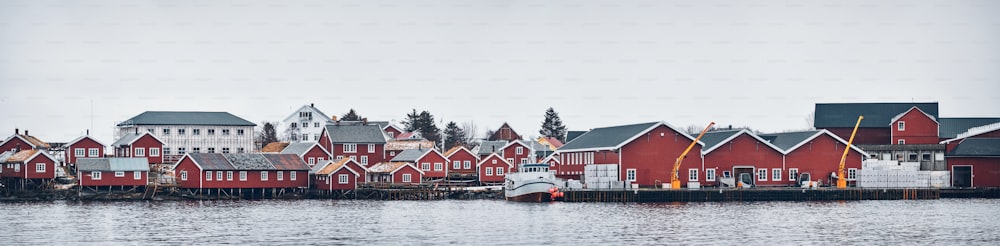 ロフォーテン島にあるレーヌの漁村のパノラマで、冬には赤いロルブの家、桟橋、漁船があります。ノルウェー