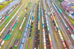 Aerial view flight over rail sorting freight station with various wagons, with many rail tracks railroad. Heavy industry landscape