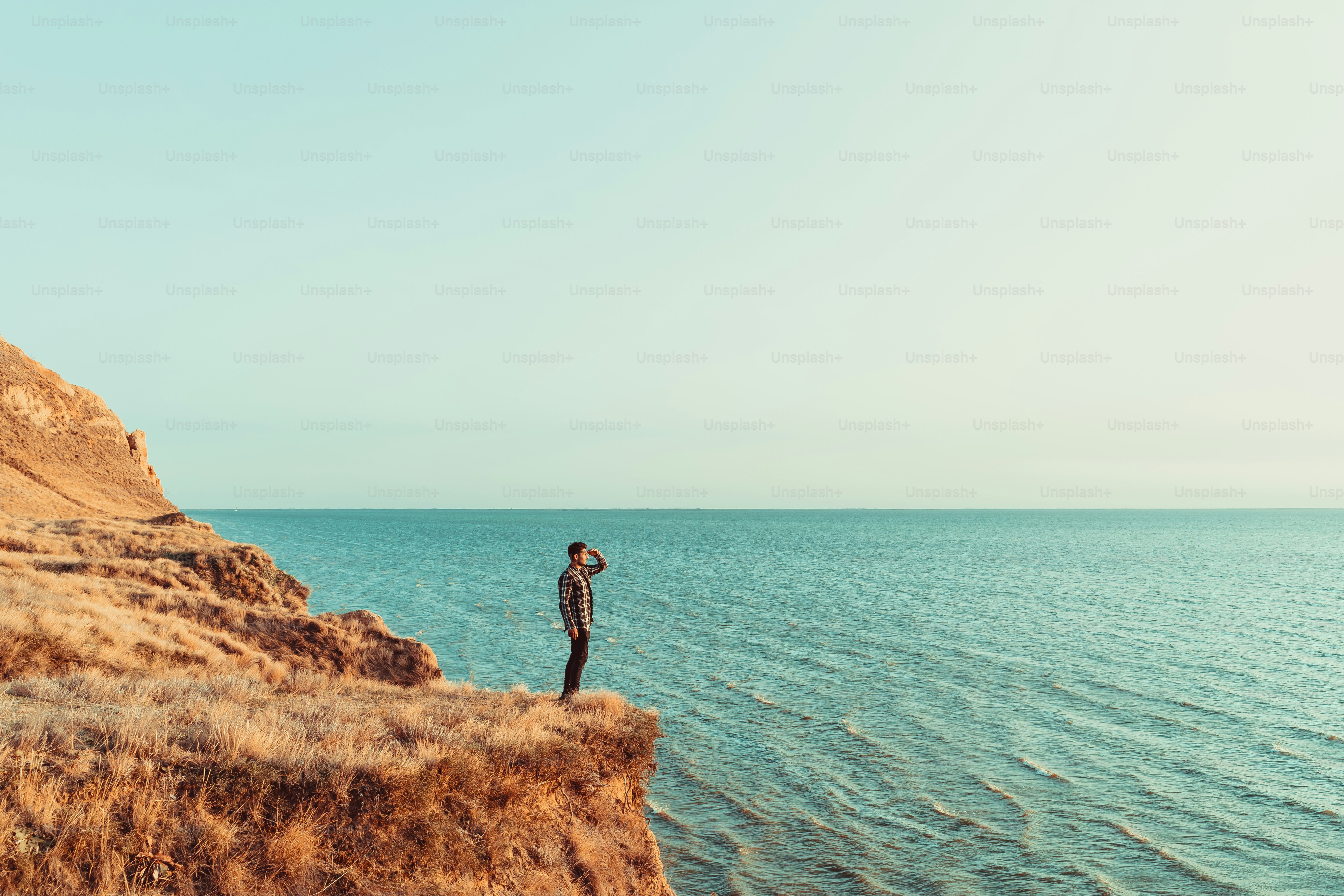 L’homme debout au sommet de la montagne au-dessus de la mer