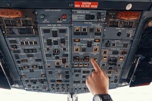 Pilot of airplane reaching out to panel overhead and toggling switch for windshield heating control