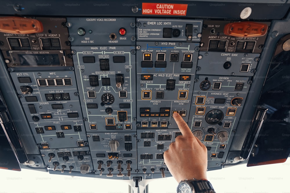 Pilot of airplane reaching out to panel overhead and toggling switch for windshield heating control