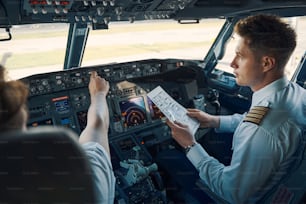 Co-Pilot mit einer Pre-Flight-Checkliste in der Hand, sitzend von einem Chefpiloten im Flugdeck